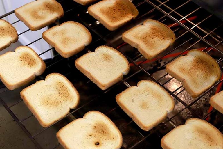 垂直图像的白面包片与不同的部分被烤成金黄色，在对角线排在烤箱的烤架上。